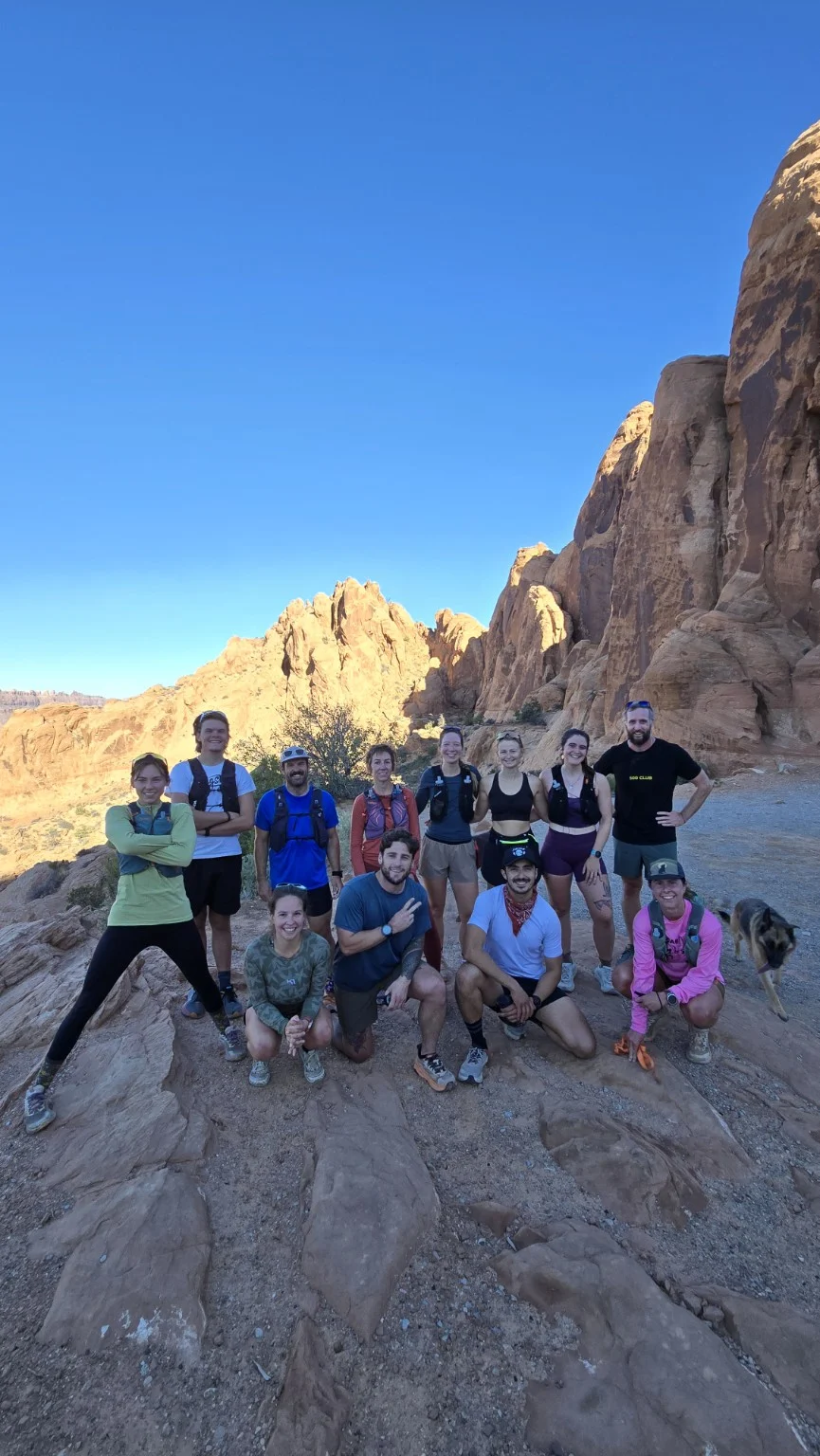 A group of runners posing together beneath canyon cliffs