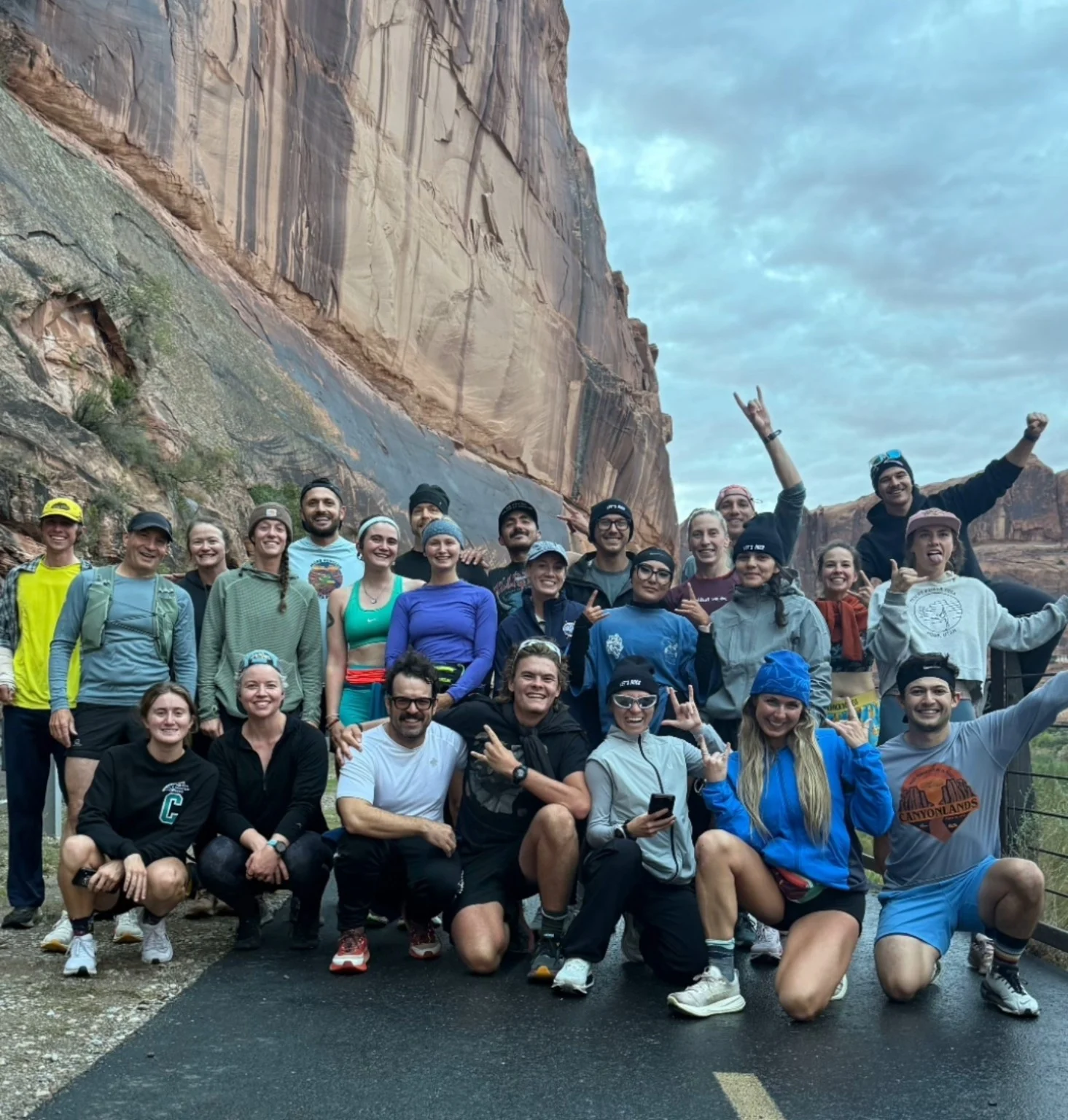 A large group of Moab Run Club runners gathered together beside a canyon wall