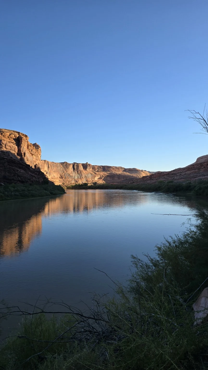 Still river water reflecting sunlit canyon cliffs